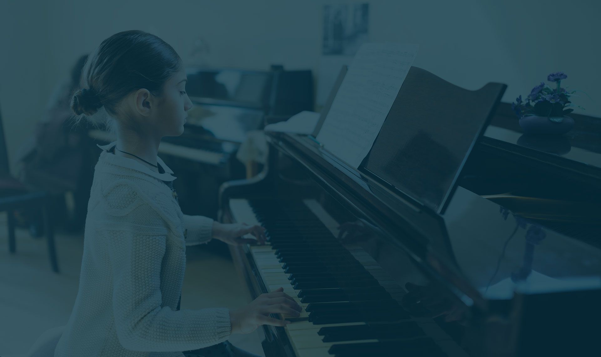Una ragazzina suona il pianoforte in una classe.