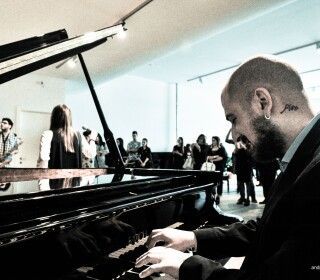 Un uomo con un tatuaggio sul collo sta suonando il pianoforte