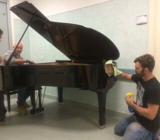 Due uomini stanno pulendo un pianoforte in una stanza.