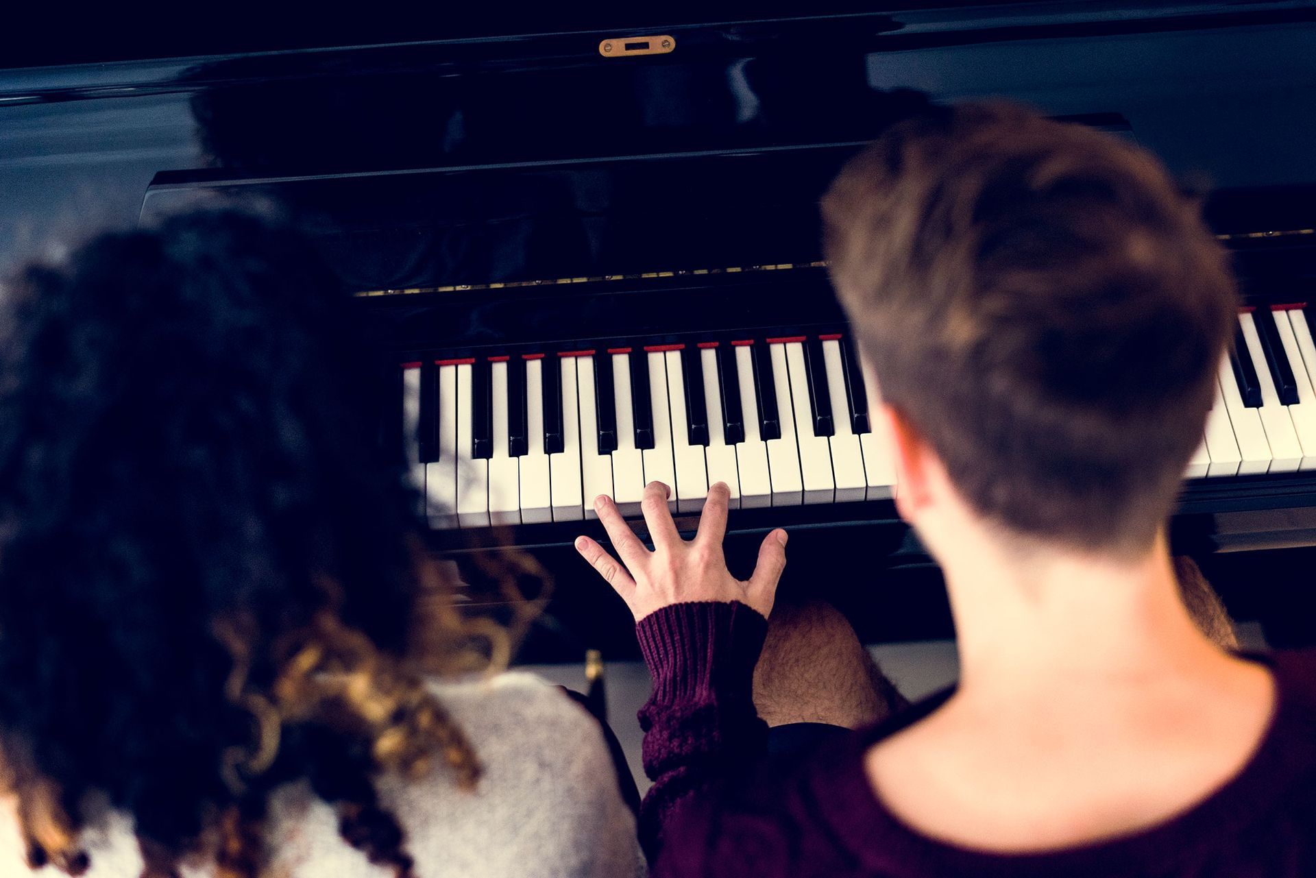 Un uomo e una donna suonano insieme il pianoforte.