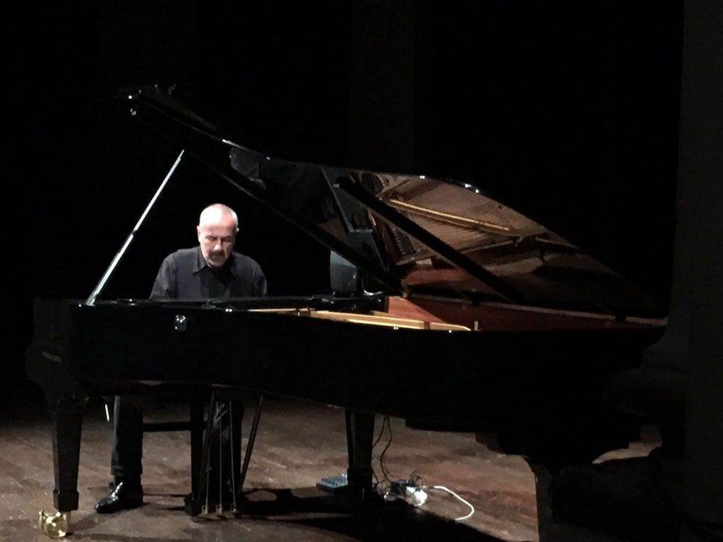 Un uomo sta suonando il pianoforte in una stanza buia.