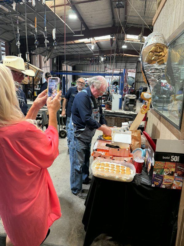 Vendor booth at an indoor market, with a man serving samples and a woman taking a photo. | Pete's Automotive