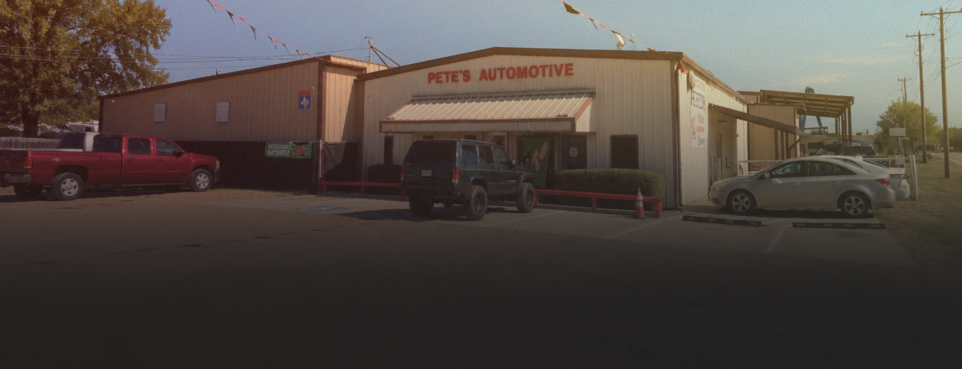 Small auto repair shop with cars parked outside at sunset | Pete's Automotive