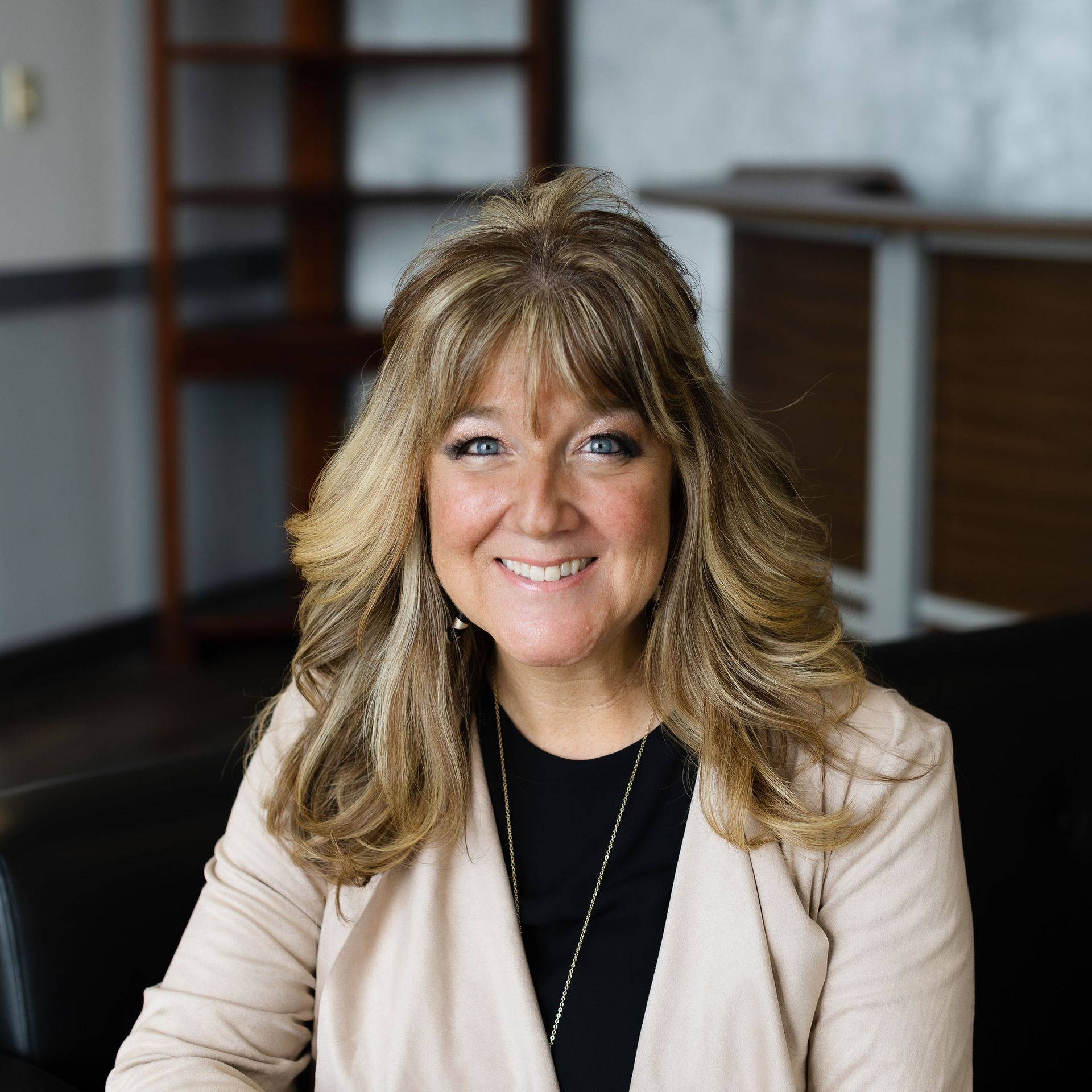 A woman wearing a black jacket and a white shirt is smiling for the camera.