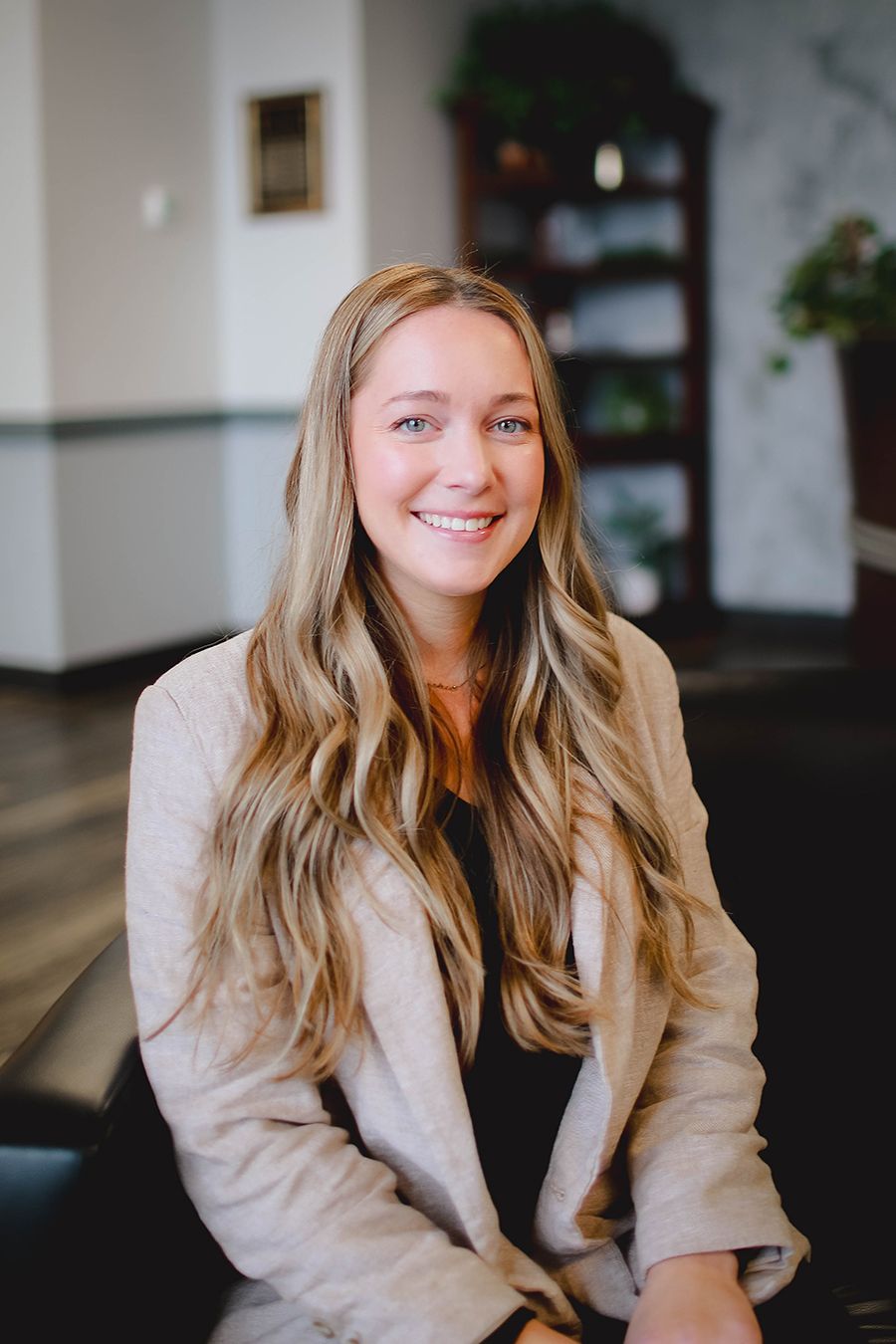 A woman is sitting on a couch and smiling for the camera.
