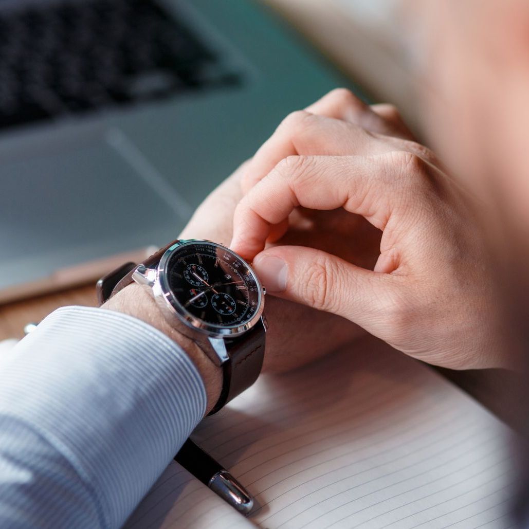 A man sitting in front of a computer checking his watch