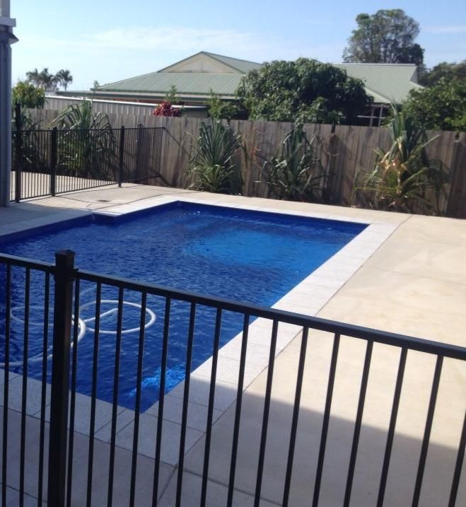 A Large Swimming Pool With a Fence Around It — DC Fencing In Wondunna, QLD