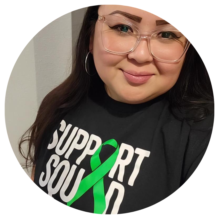 Person wearing glasses and a black shirt with a green ribbon and text that reads