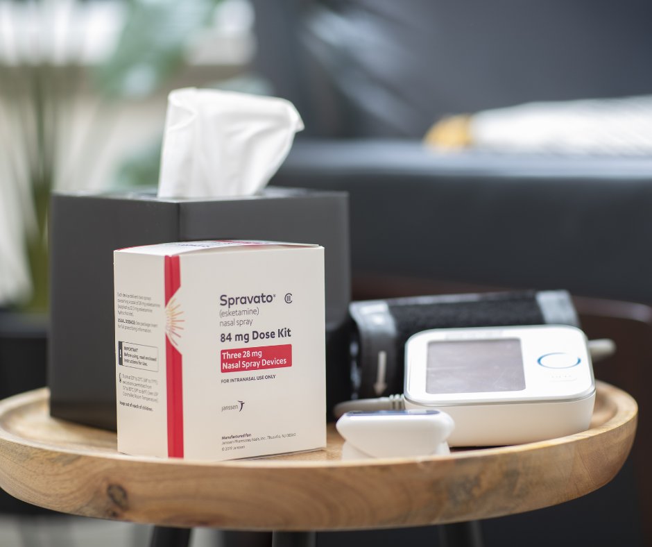 Box of Synovator drug with tissue box and blood pressure monitor on a wooden tray.