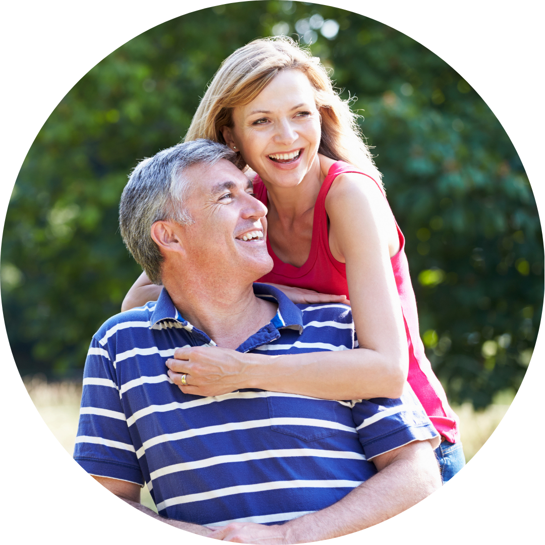 Woman embracing a man outdoors, both smiling. The man wears a striped shirt.