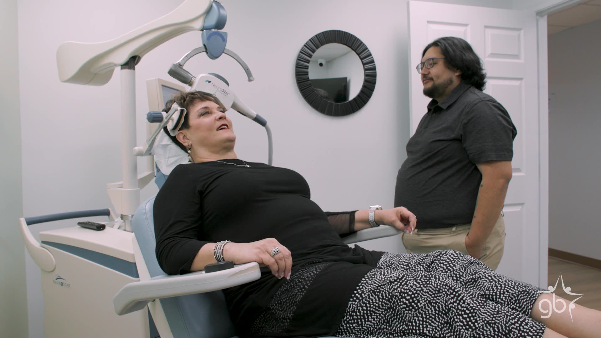 Woman in dental chair, looking up at dental equipment, man in room.