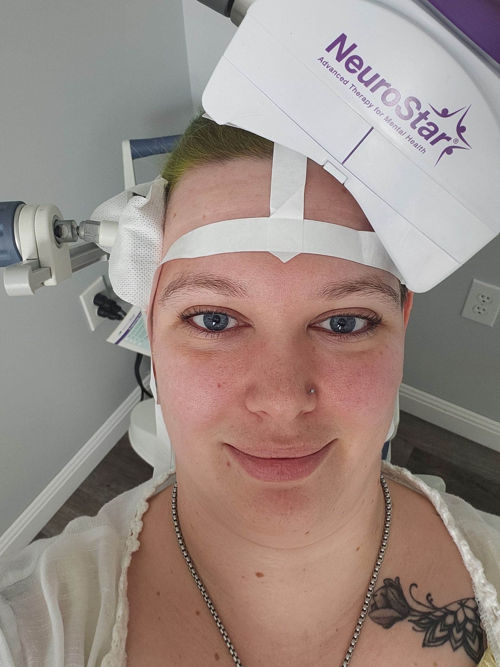 Woman with medical device on head, smiling, in a medical setting.