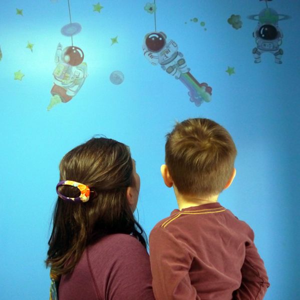 A woman and a child are looking at a wall with astronauts on it.