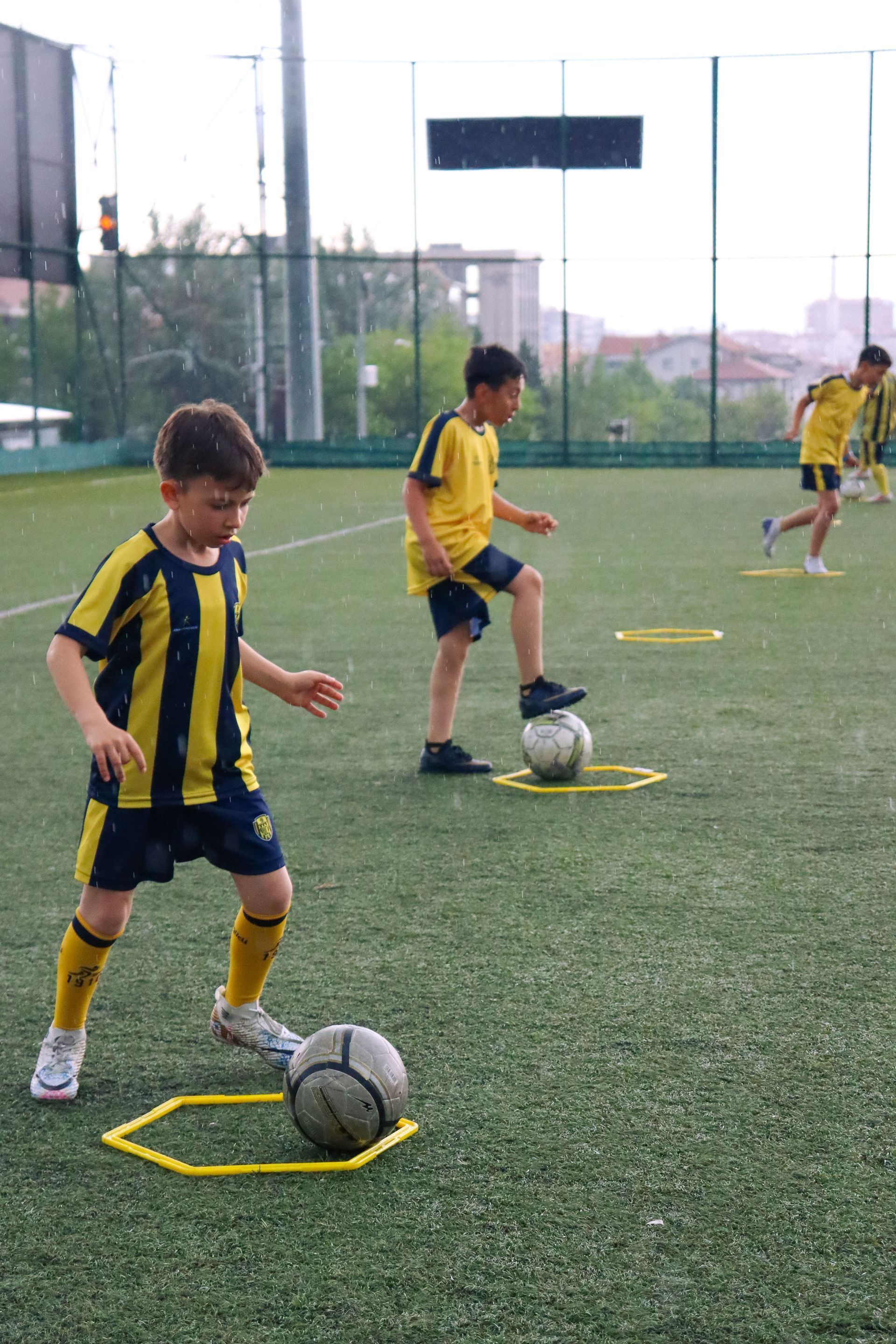Boys are on a turf field doing soccer drills. They are wearing yellow and blue jerseys.