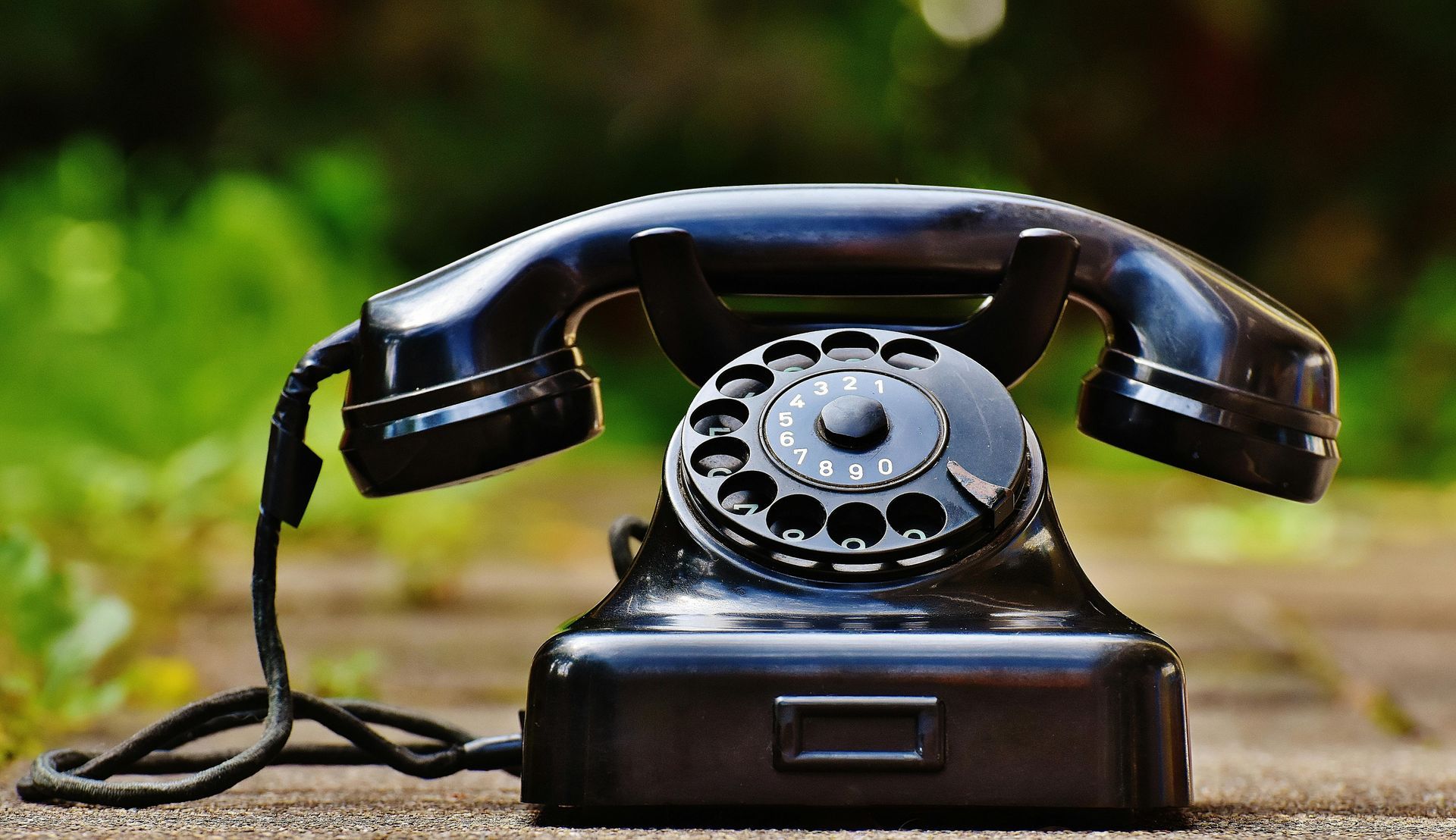 An old-fashioned telephone siting on ground.