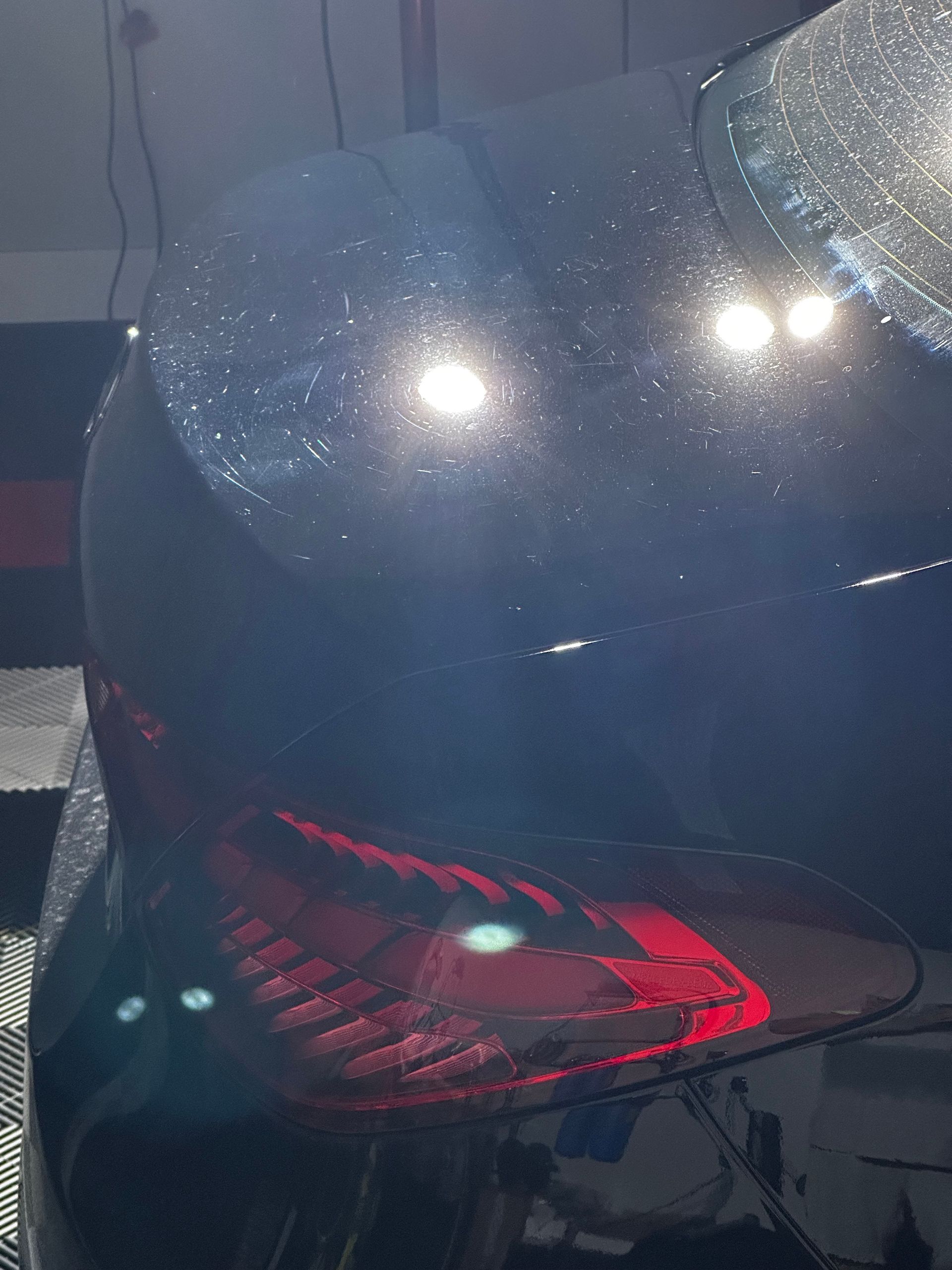 Close-up of a glossy dark helmet with a red interior and bright light reflections, resting on a chair