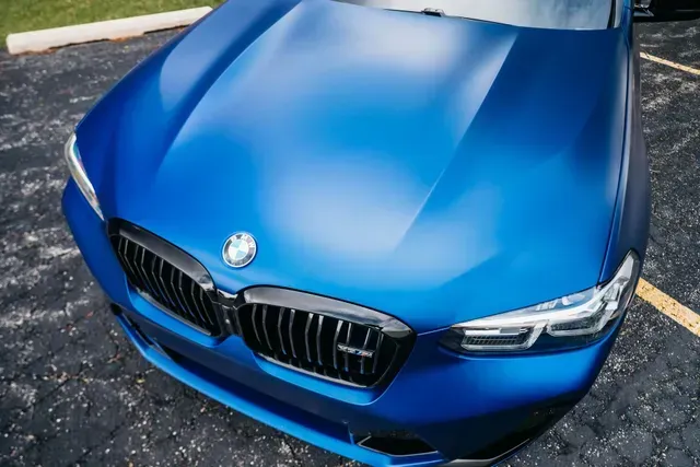 Front view of a blue BMW parked on pavement