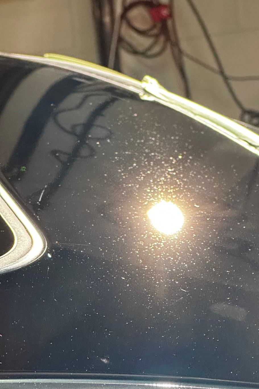 Close-up of a black car roof with bright reflections and a yellow pinstripe