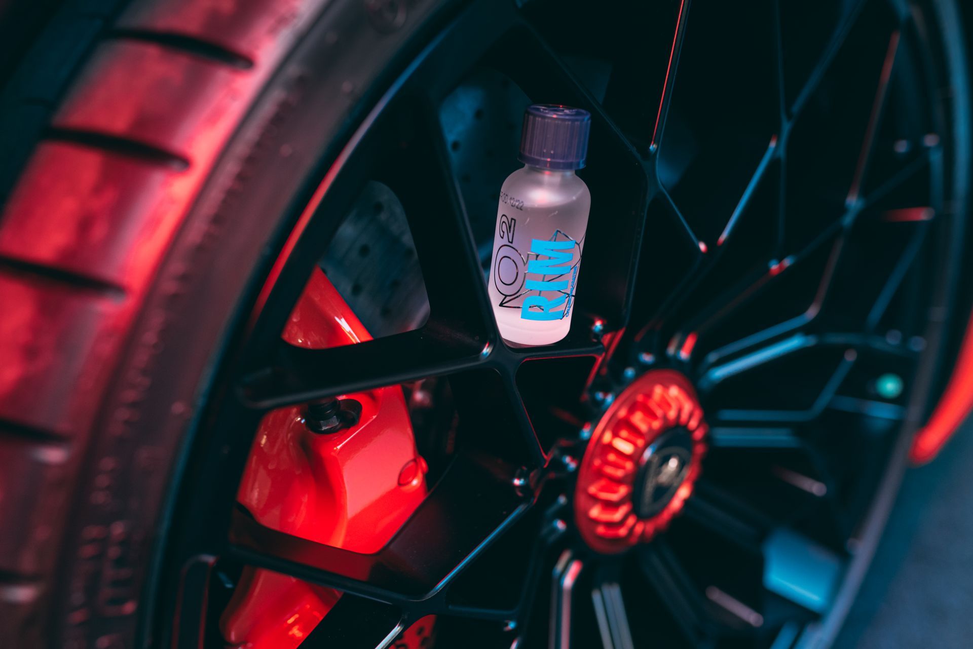 Water bottle wedged in a black car wheel rim lit by red and blue lights