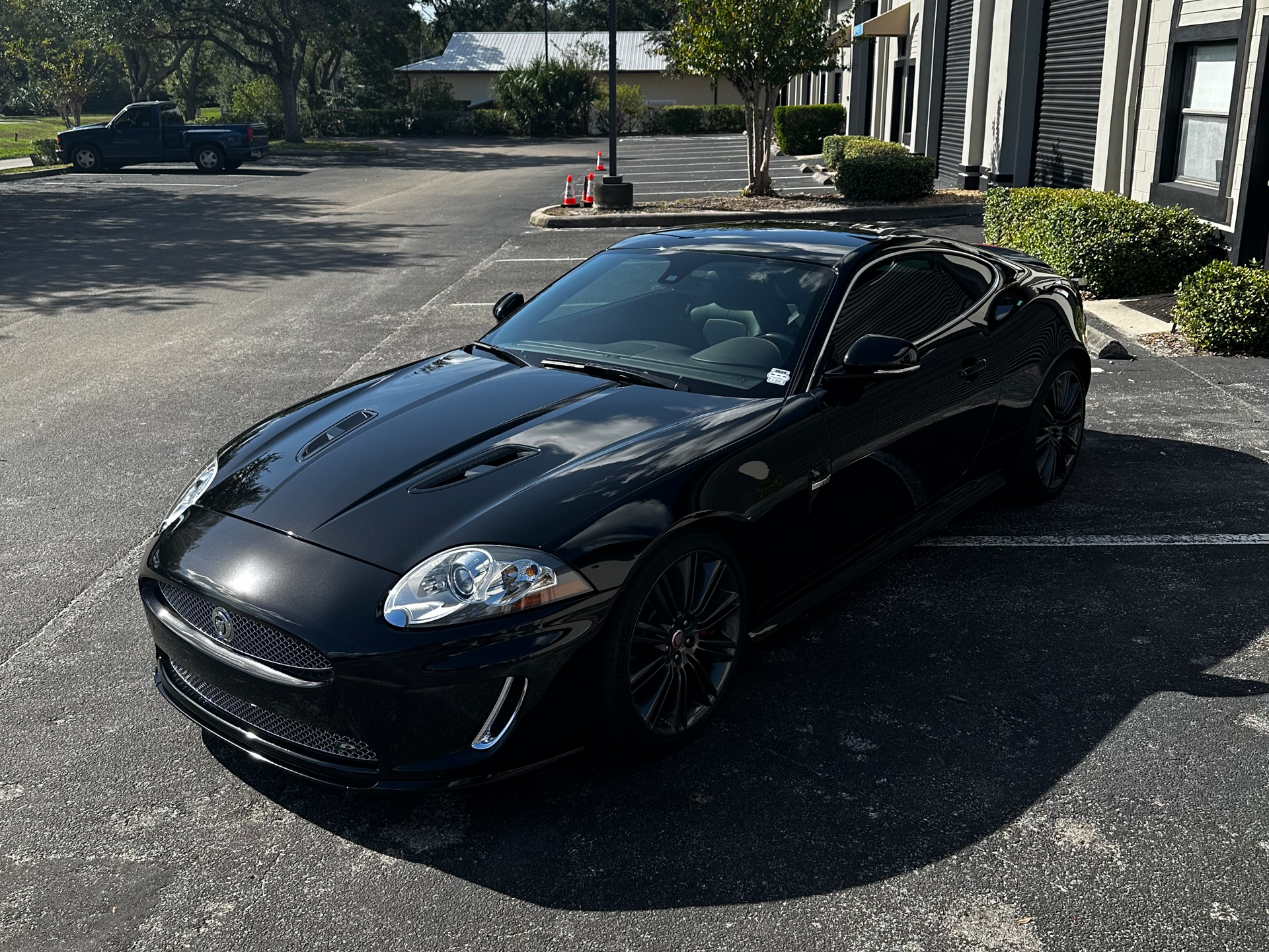 Black sports car parked outside an office building on a sunny day