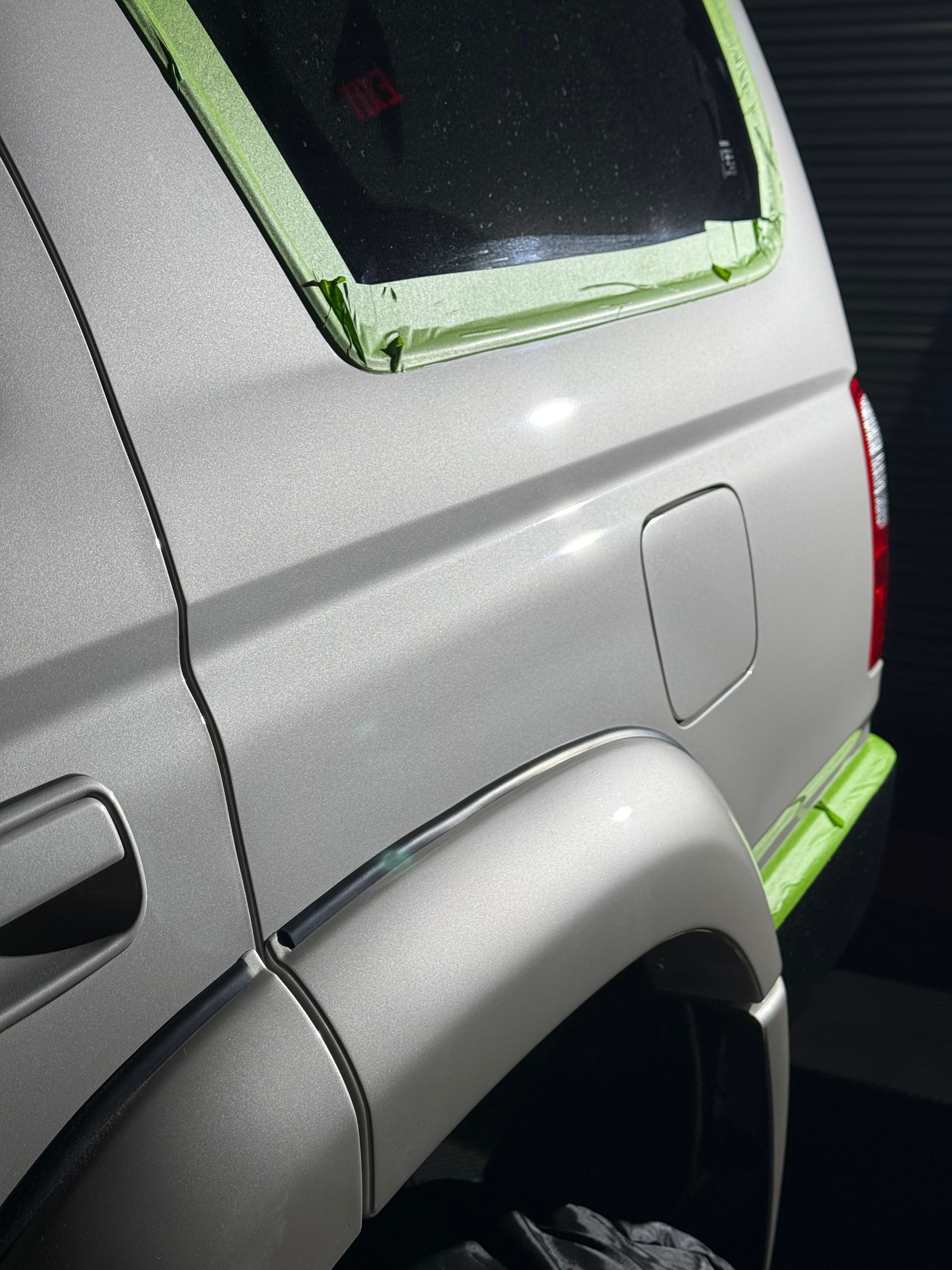 Gray SUV with green trim around the rear window and bumper, shown close-up from the side.