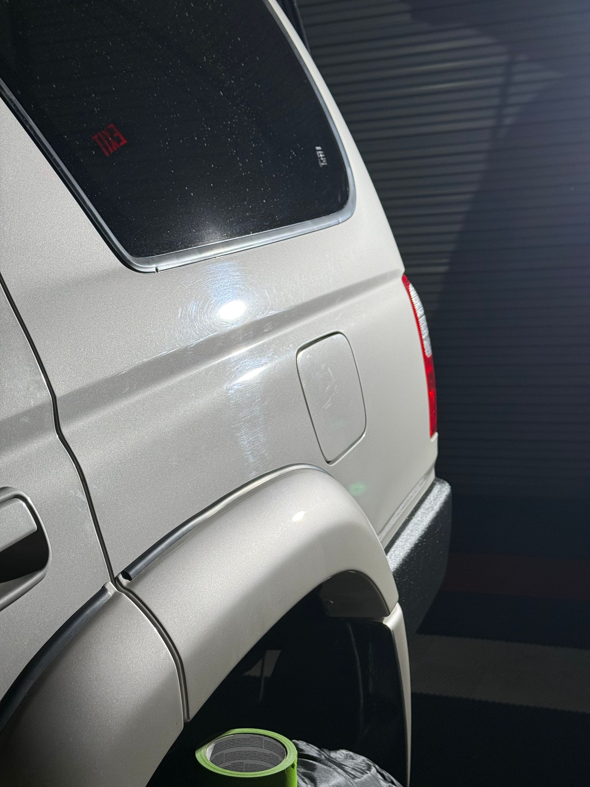 Silver SUV rear side in a garage, showing the wheel well and fuel door.