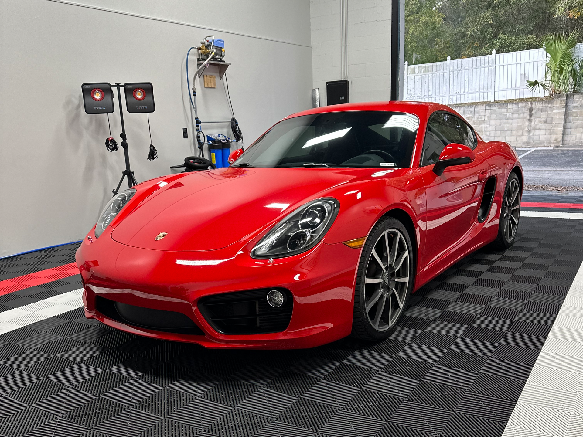 Red sports coupe in a studio with bright lighting and patterned floor