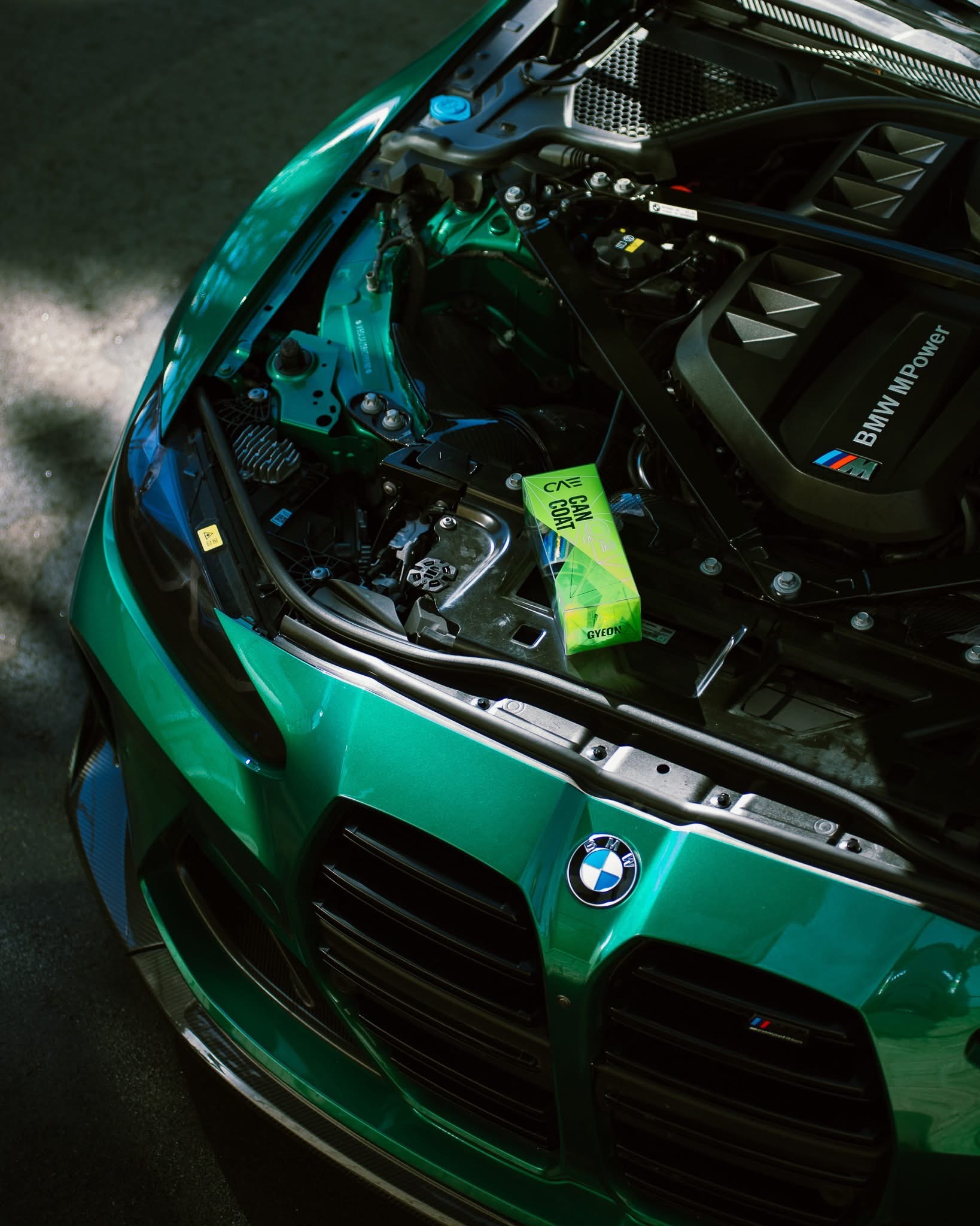 Green BMW sports car with its hood open, showing the engine at an auto show
