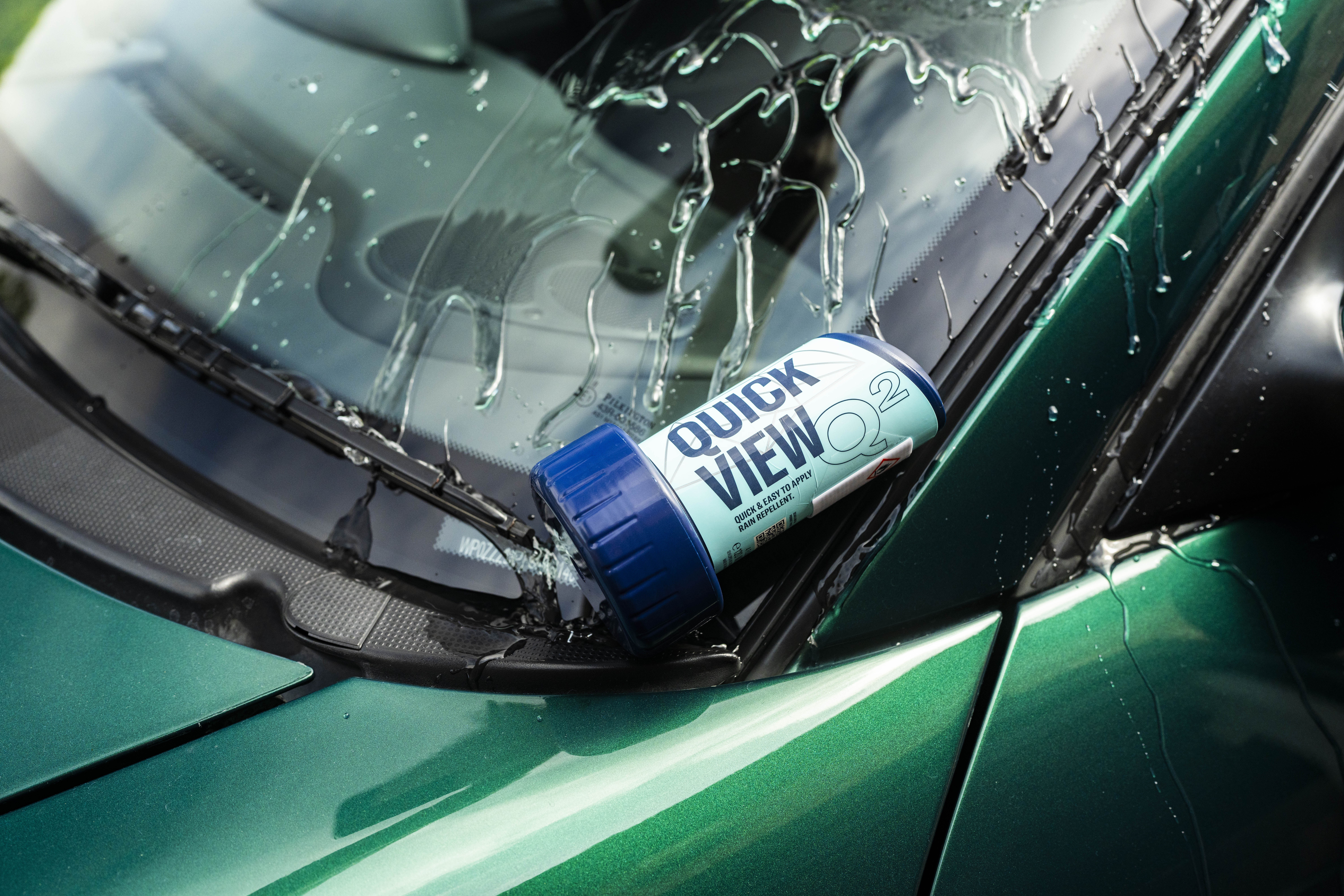 Blue-and-white Quick View can on a wet green car windshield with raindrops