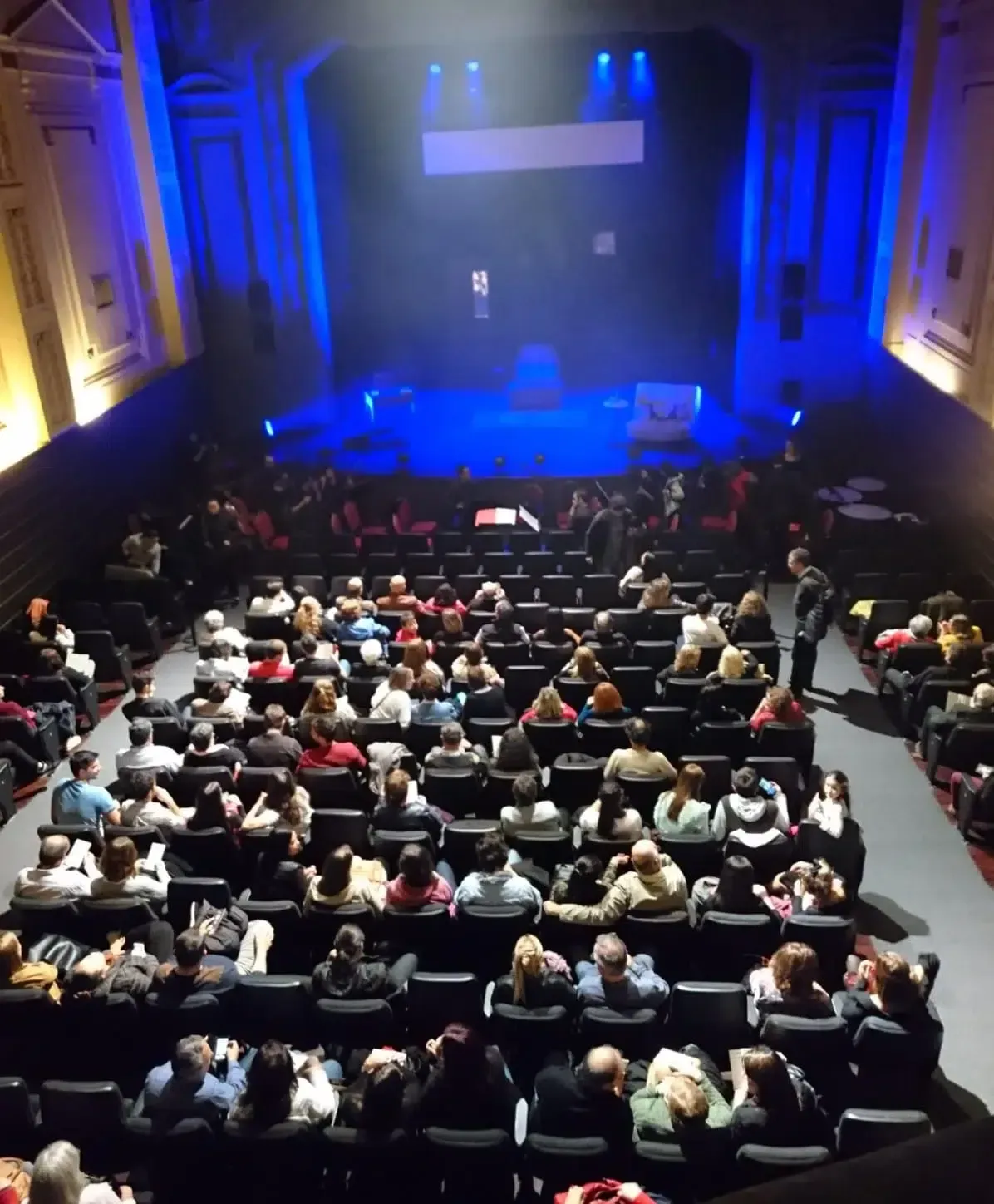 Una multitud de personas están sentadas en un auditorio viendo un espectáculo.