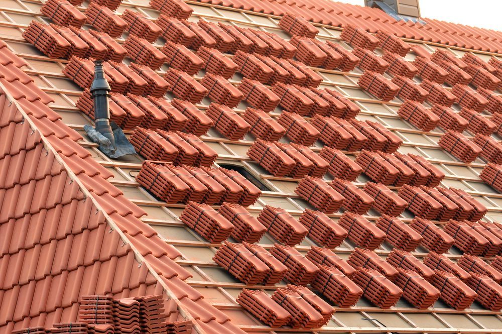 Roof With Stacks of Red Tiles Being Installed — Boostn Pty Ltd in Glastonbury, QLD