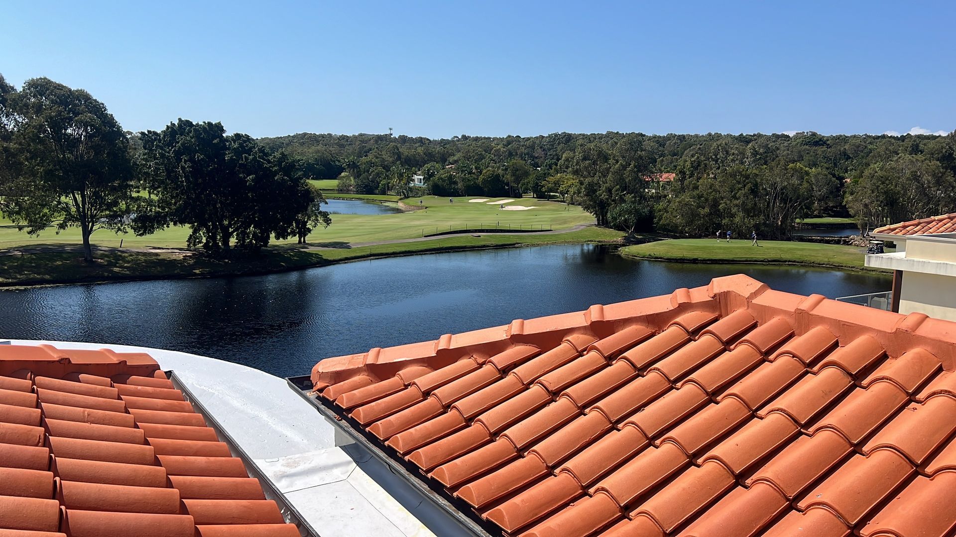 Terracotta tile roof with a view of a lake, golf course, and trees under a clear blue sky. — Boostn Pty Ltd in Glastonbury, QLD