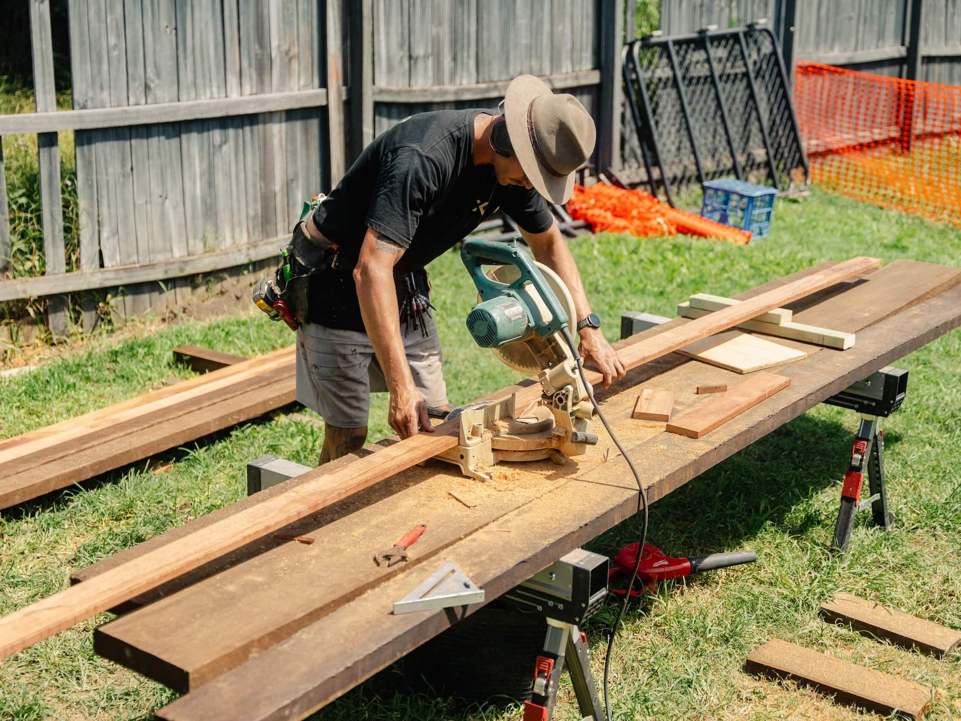 Worker using a circular saw to cut wood planks outdoors on a makeshift workbench