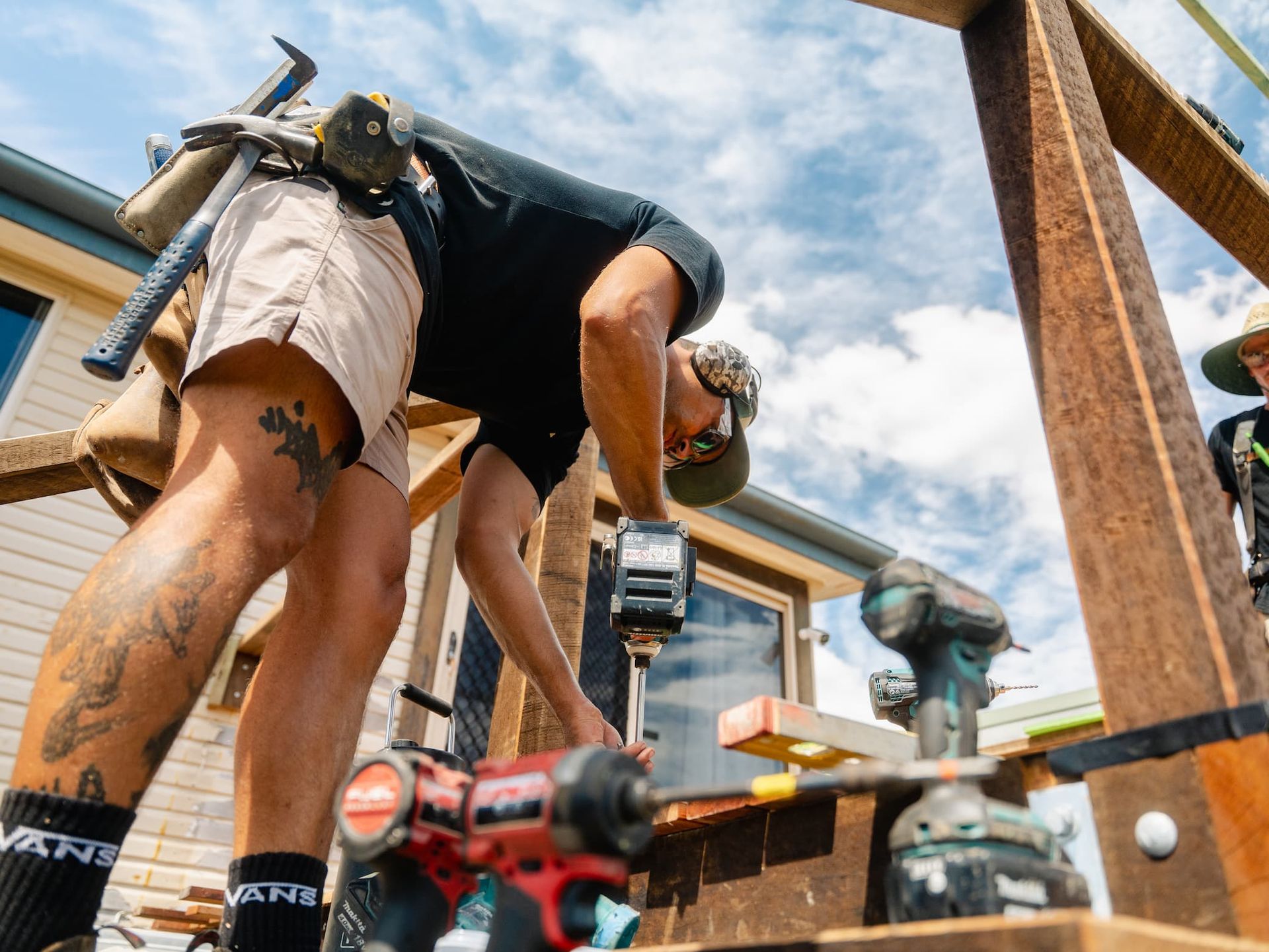 Worker carrying a large sheet of wood through a bright room under renovation
