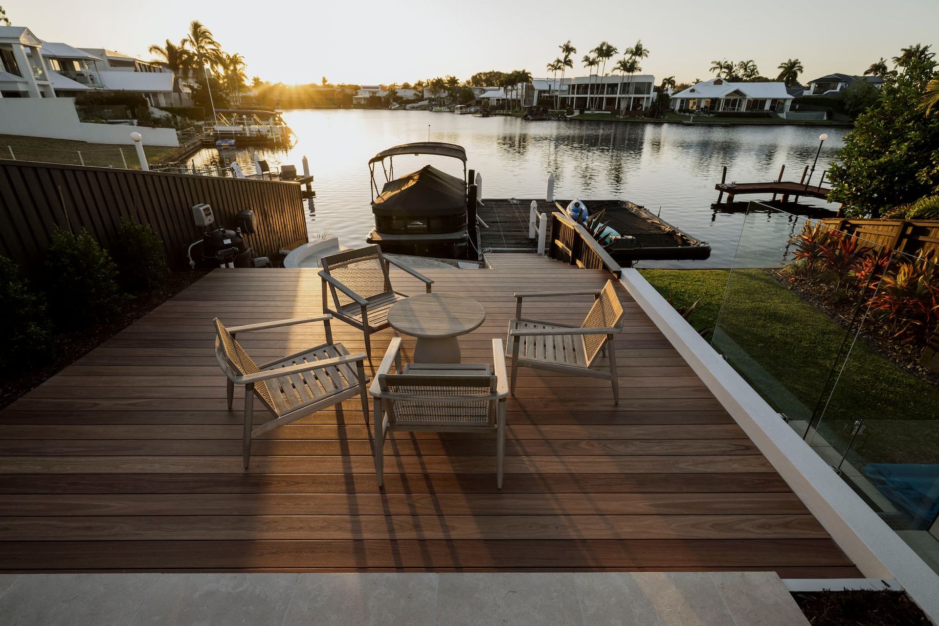 Patio dining set on a wooden deck overlooking a calm canal at sunset