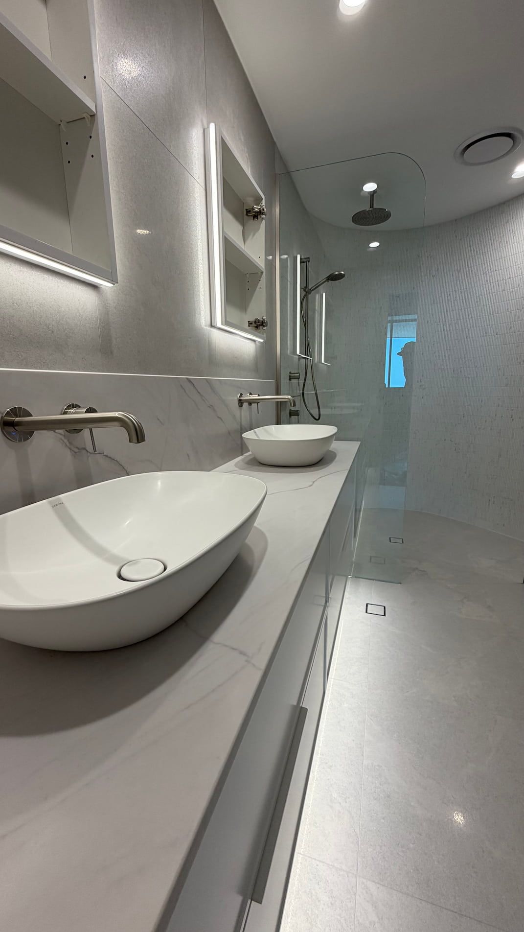 Modern bathroom with double vanity, toilet, tiled floor, and neutral wood finishes