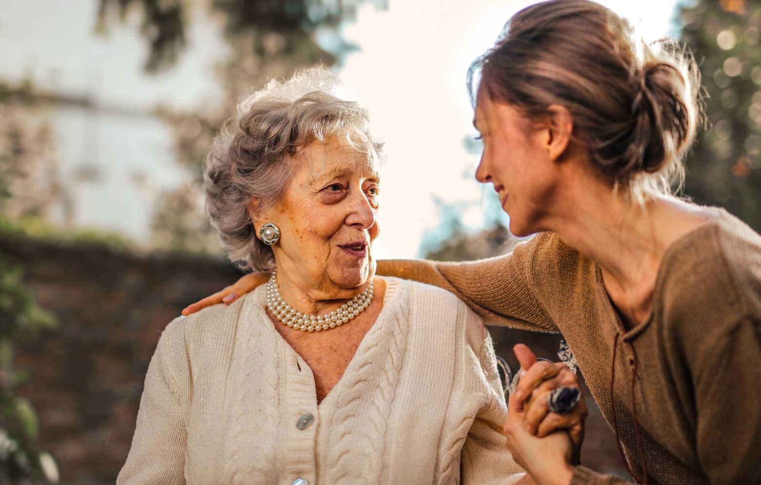 A young woman is holding the hand of an older woman.
