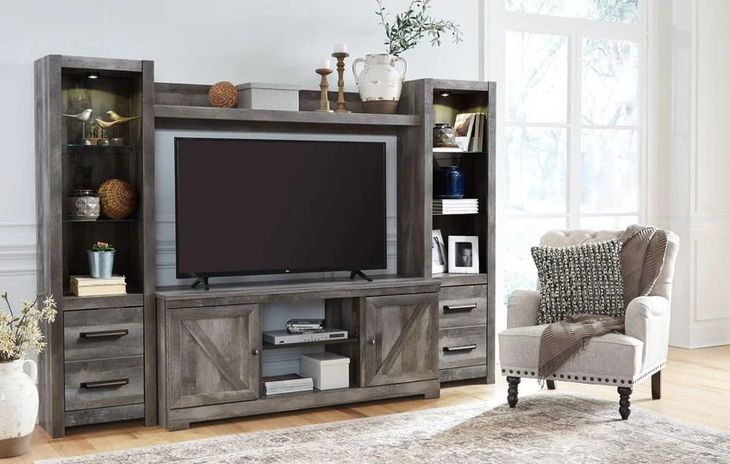 Gray wooden entertainment center with TV, shelves, and accent chair.