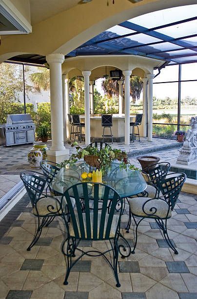 Outdoor dining area with a table and chairs, with a bar and grill in the background.