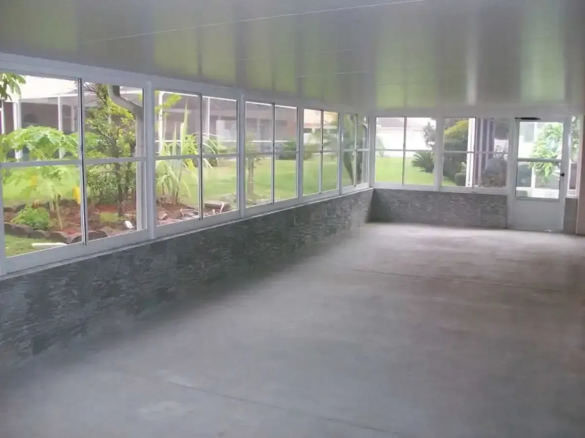 Sunroom with floor-to-ceiling windows, gray floor, white trim, and a door to the outdoors.