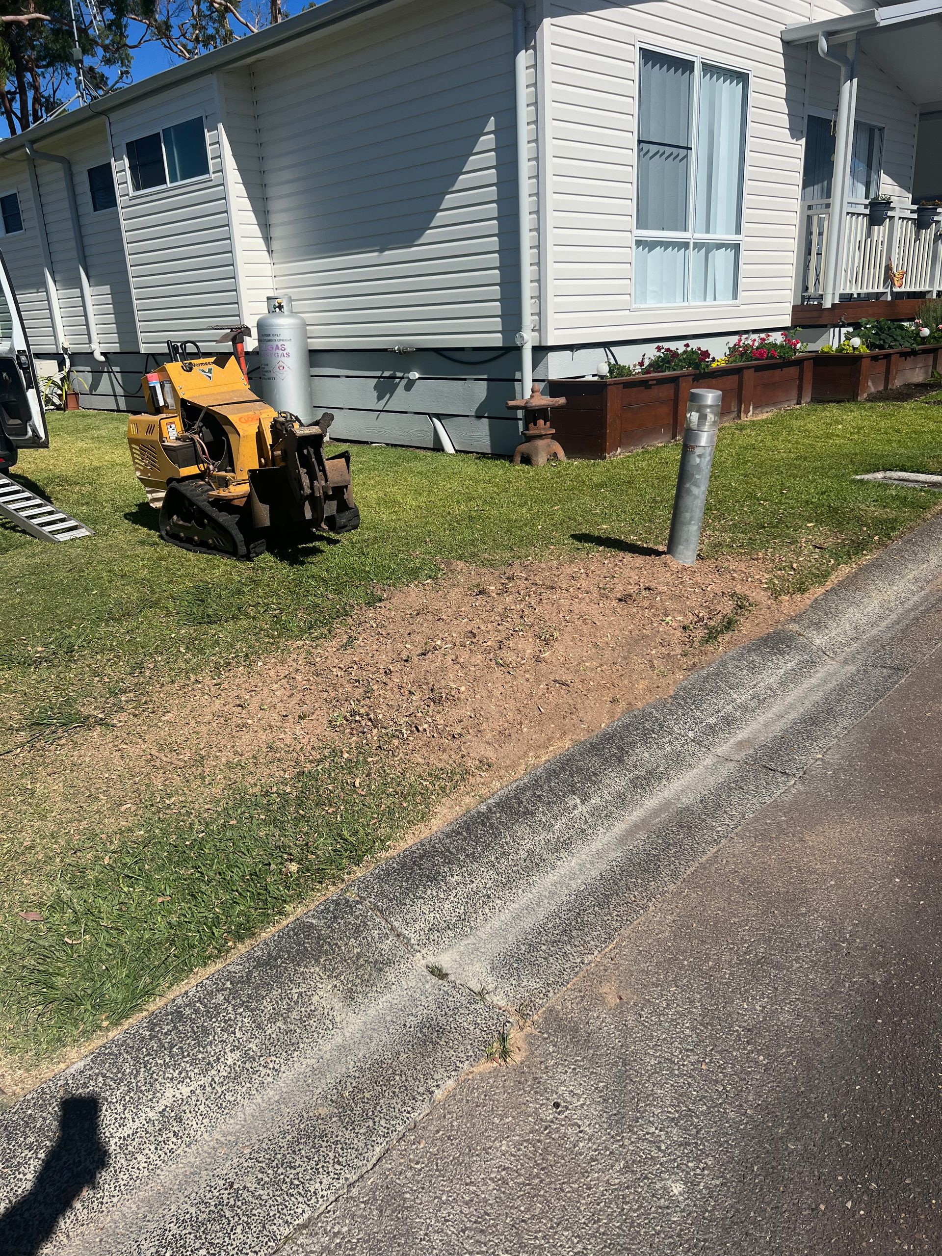 Stump remover machine parked in a backyard next to the house — Central Coast Tree Removal In Wyongah, NSW