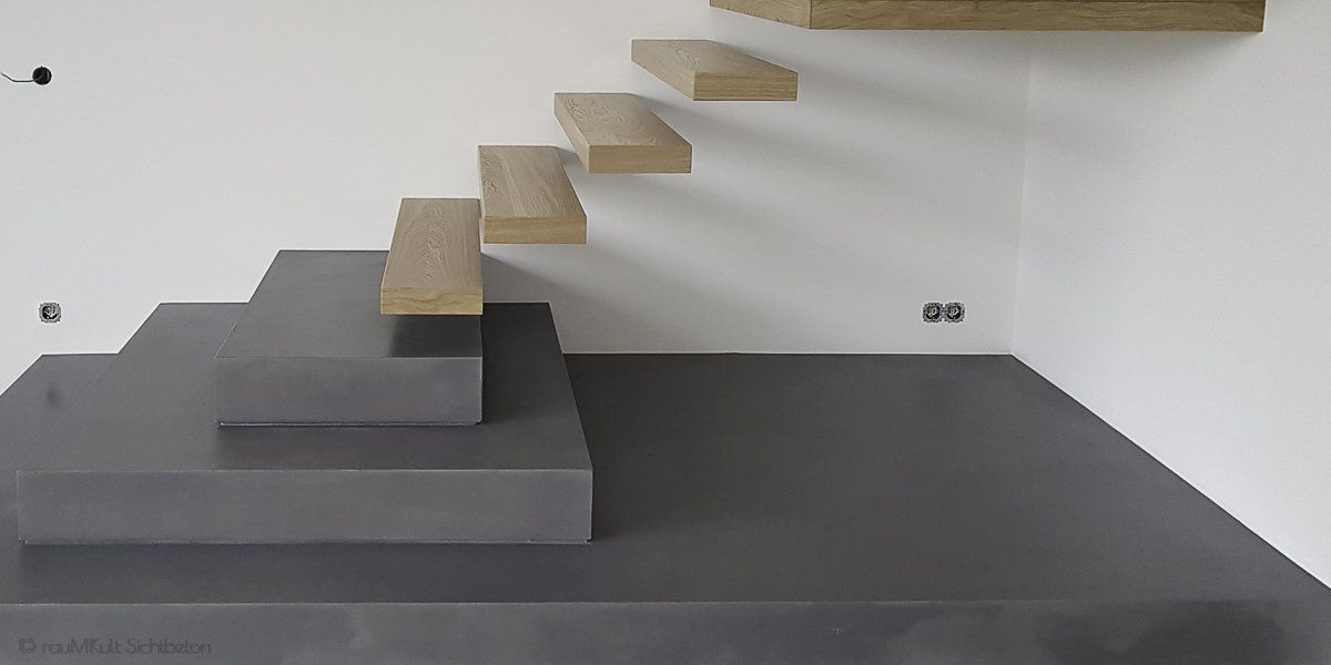 Eine in schwarz Beschichtete Treppe mit Mikrozement. 3 Stufen, gefolgt con weiteren Holztreppenstufen die direkt an der Wand sind