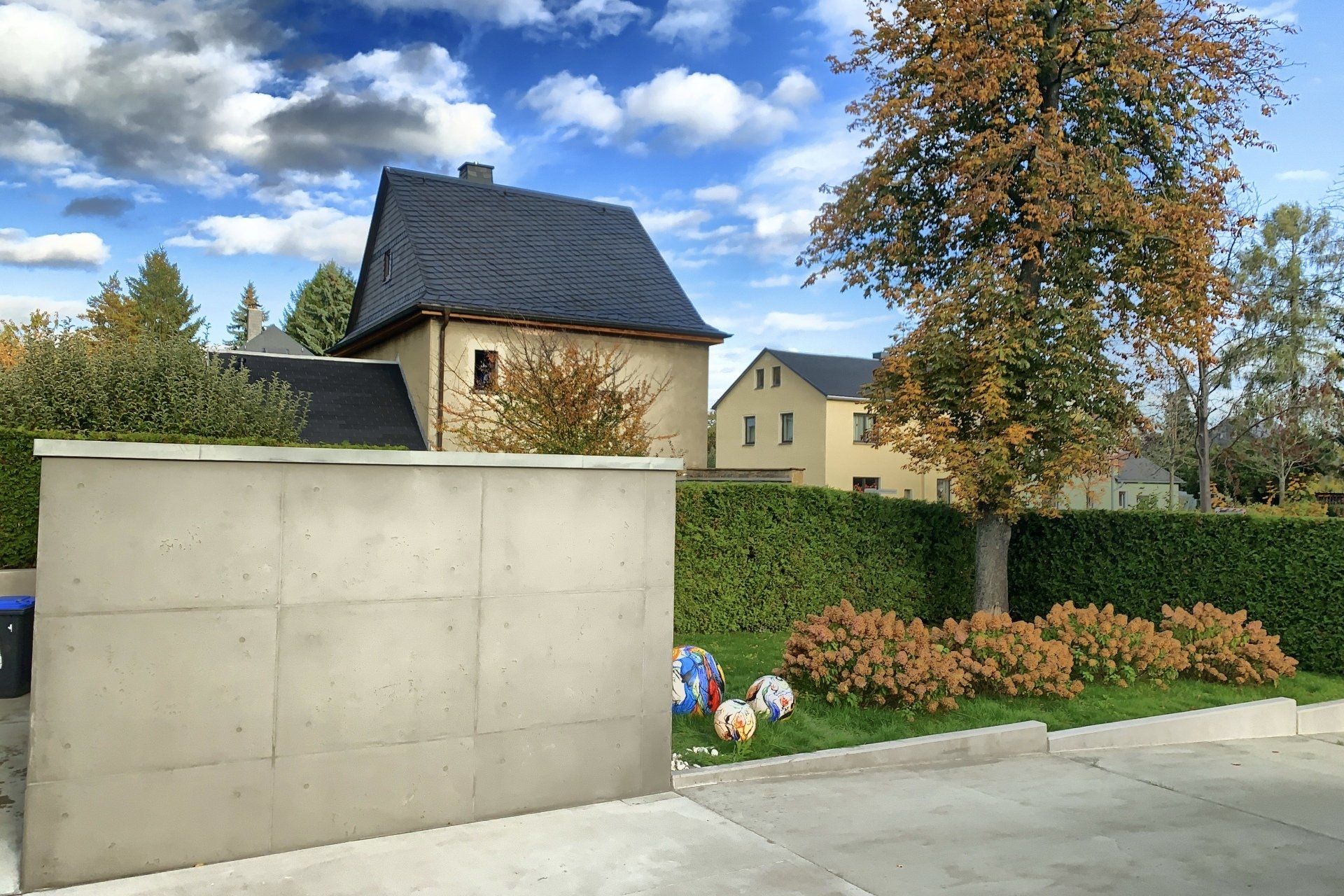 Betonoptik in Betongrau an einer Fassade von rauMKult Sichtbeton, in der Umgebung sind Bäume und Sträucher