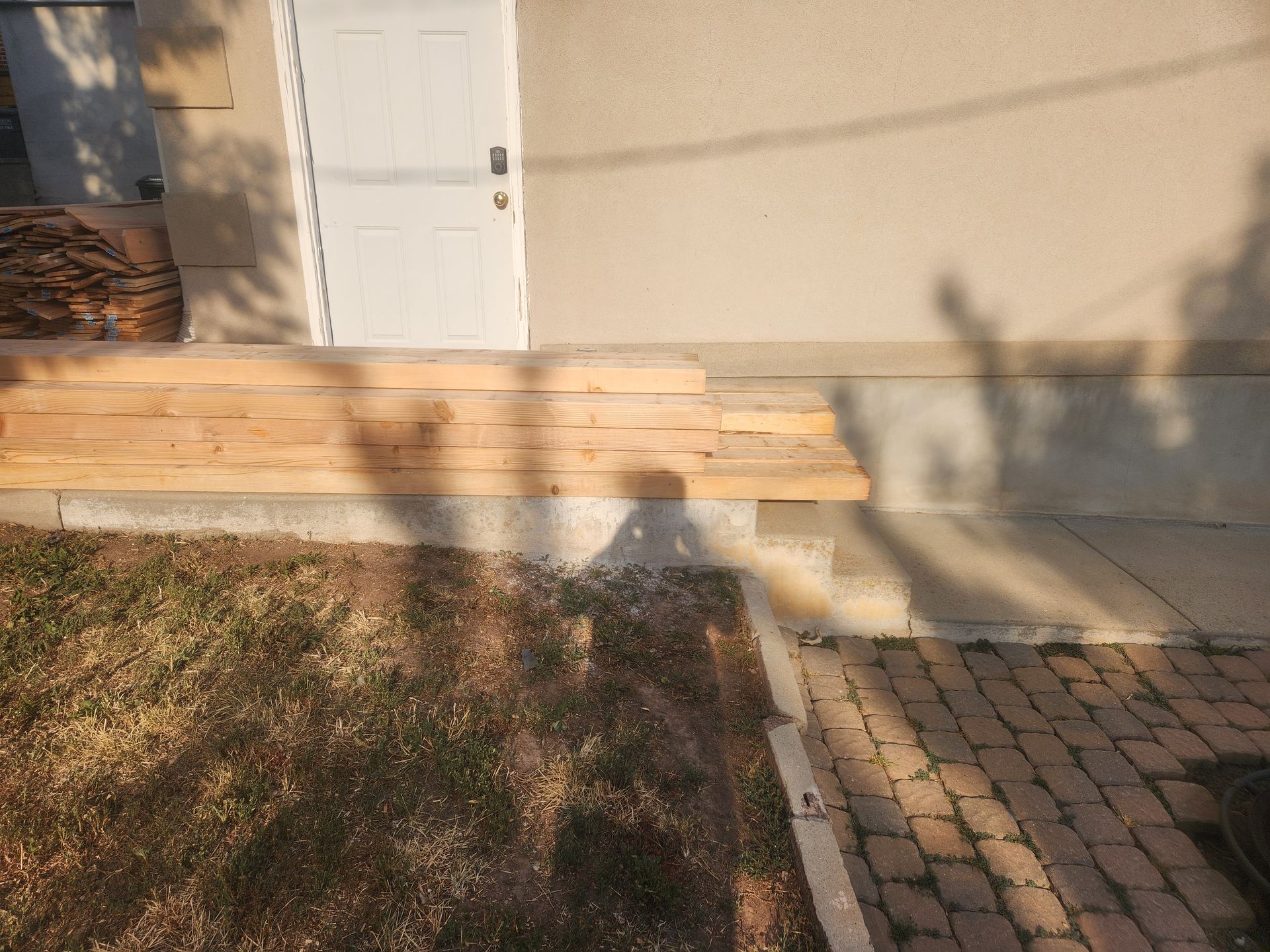 Stone steps and walkway leading to a beige house with a white door in sunlight