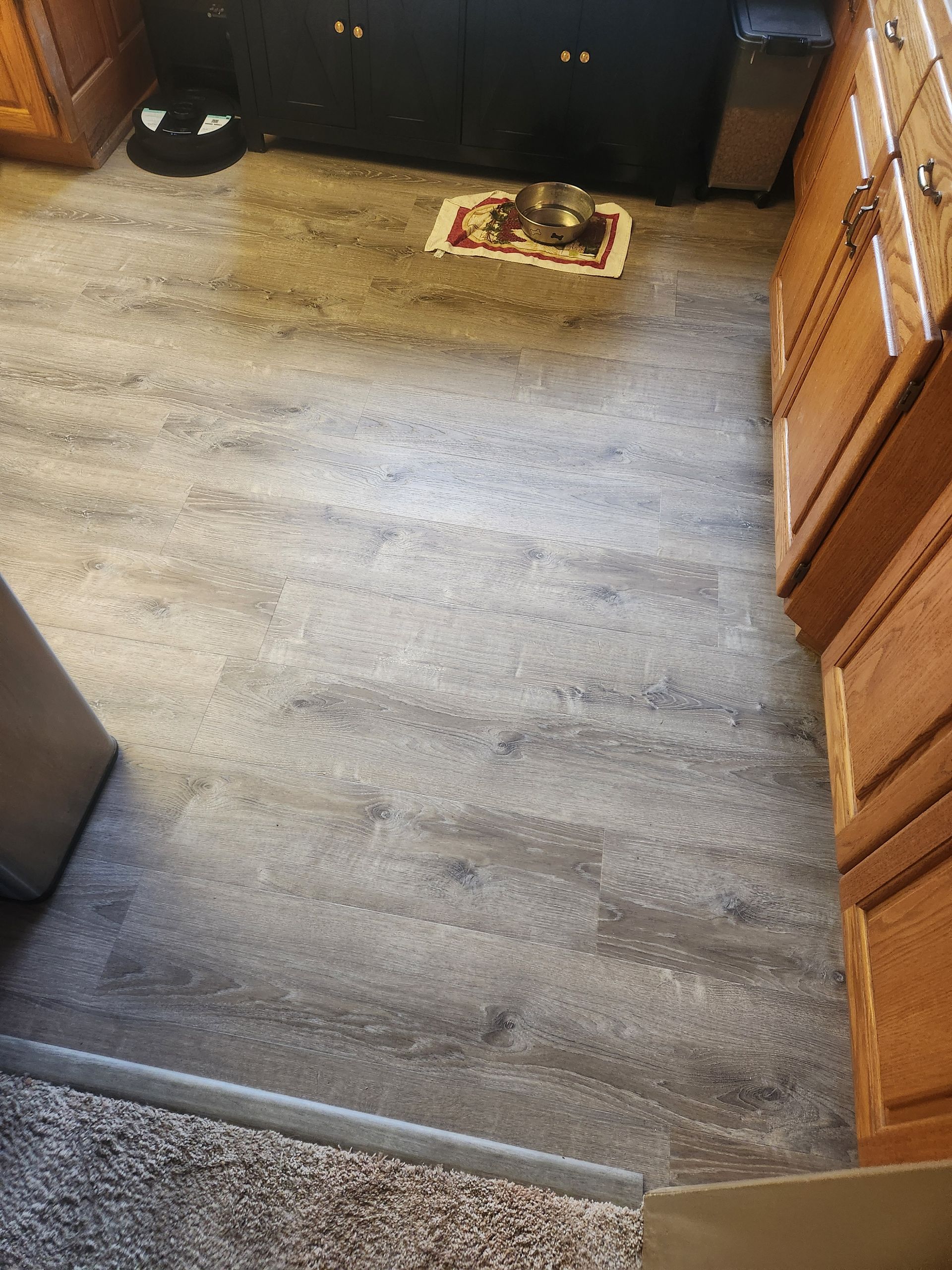 Kitchen floor with a striped rug near dark cabinets and wooden cupboards.