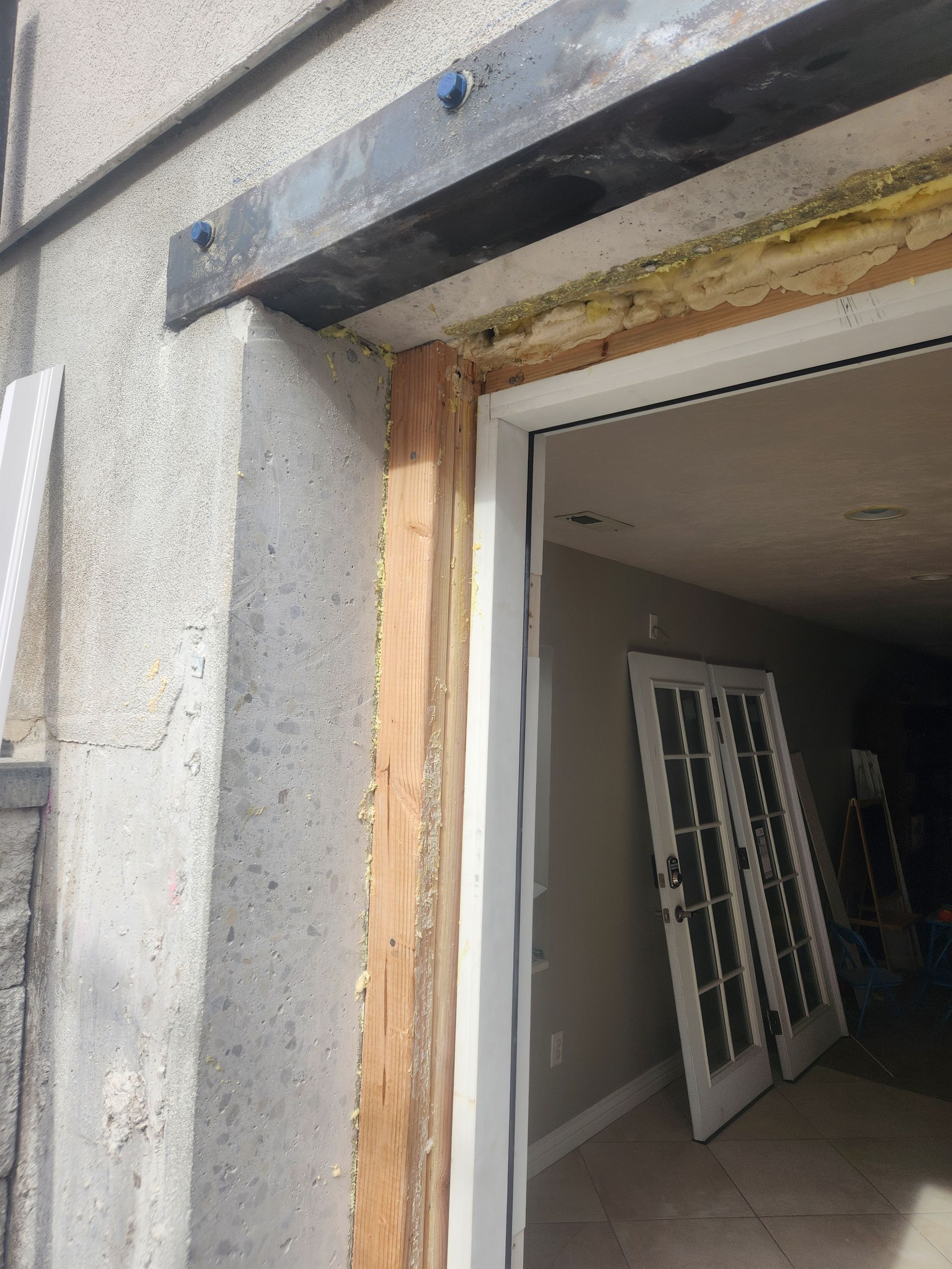 Partially finished doorway with exposed wood framing and a door leaning inside a construction site