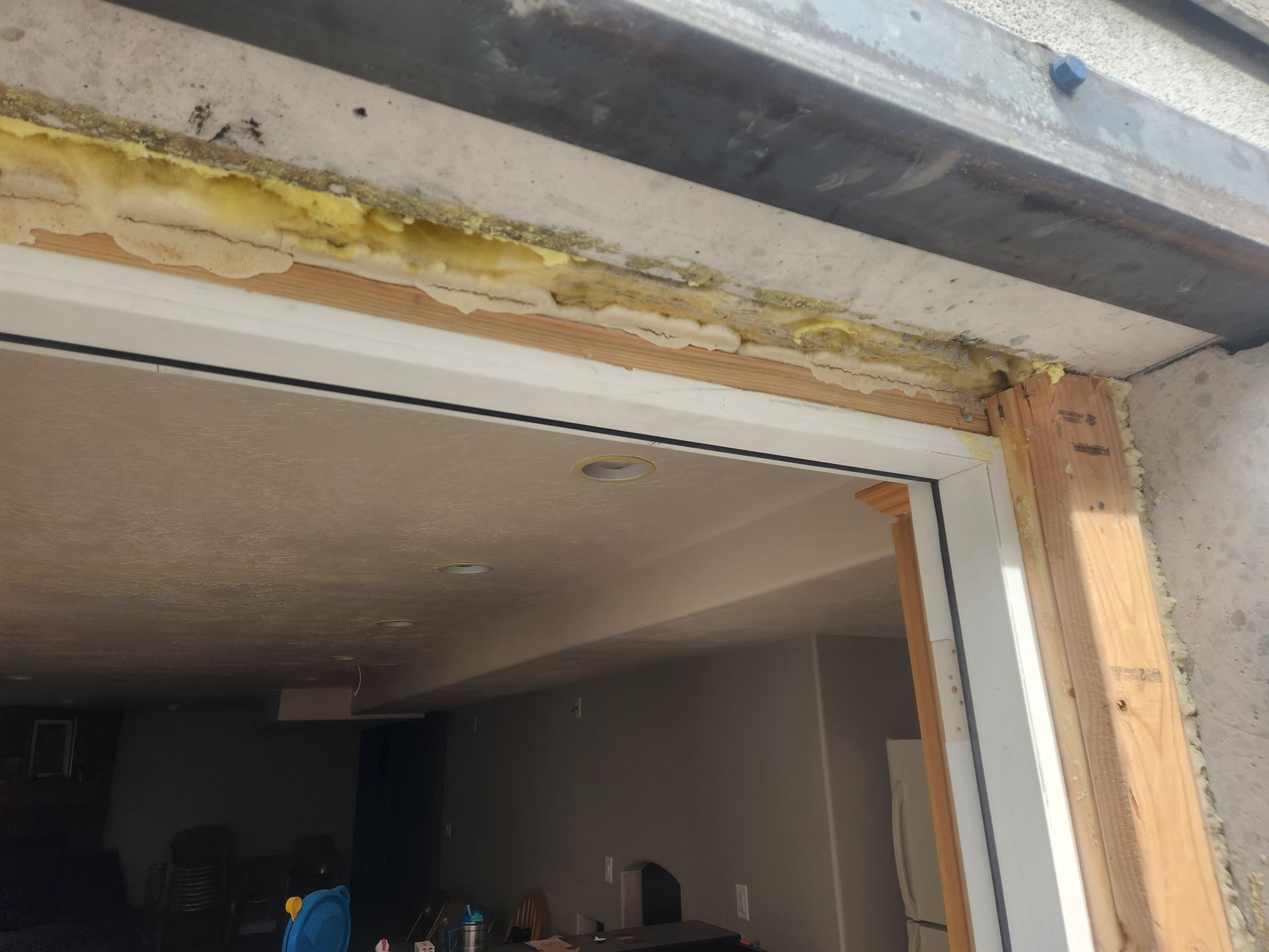 Partially finished doorway with exposed wood and insulation above, opening into a dim interior room