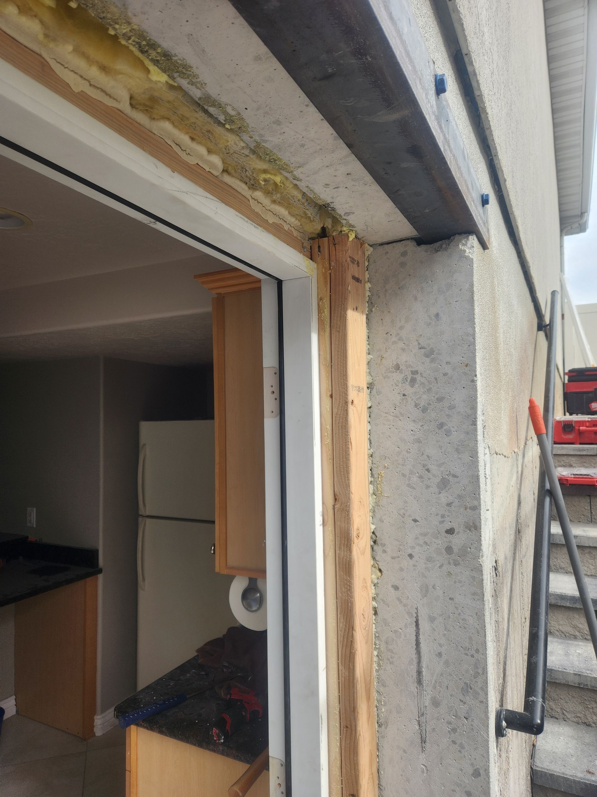 Damaged garage doorway with exposed insulation and unfinished concrete exterior
