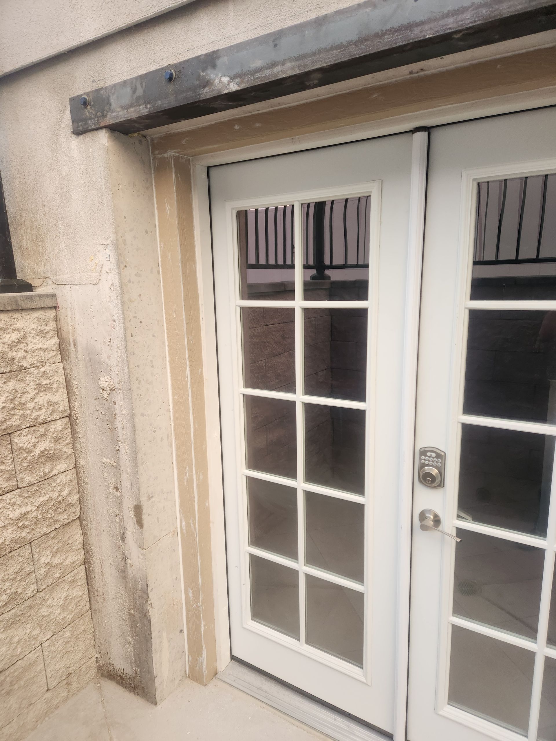 White double glass French doors with a metal awning and beige stone wall outside