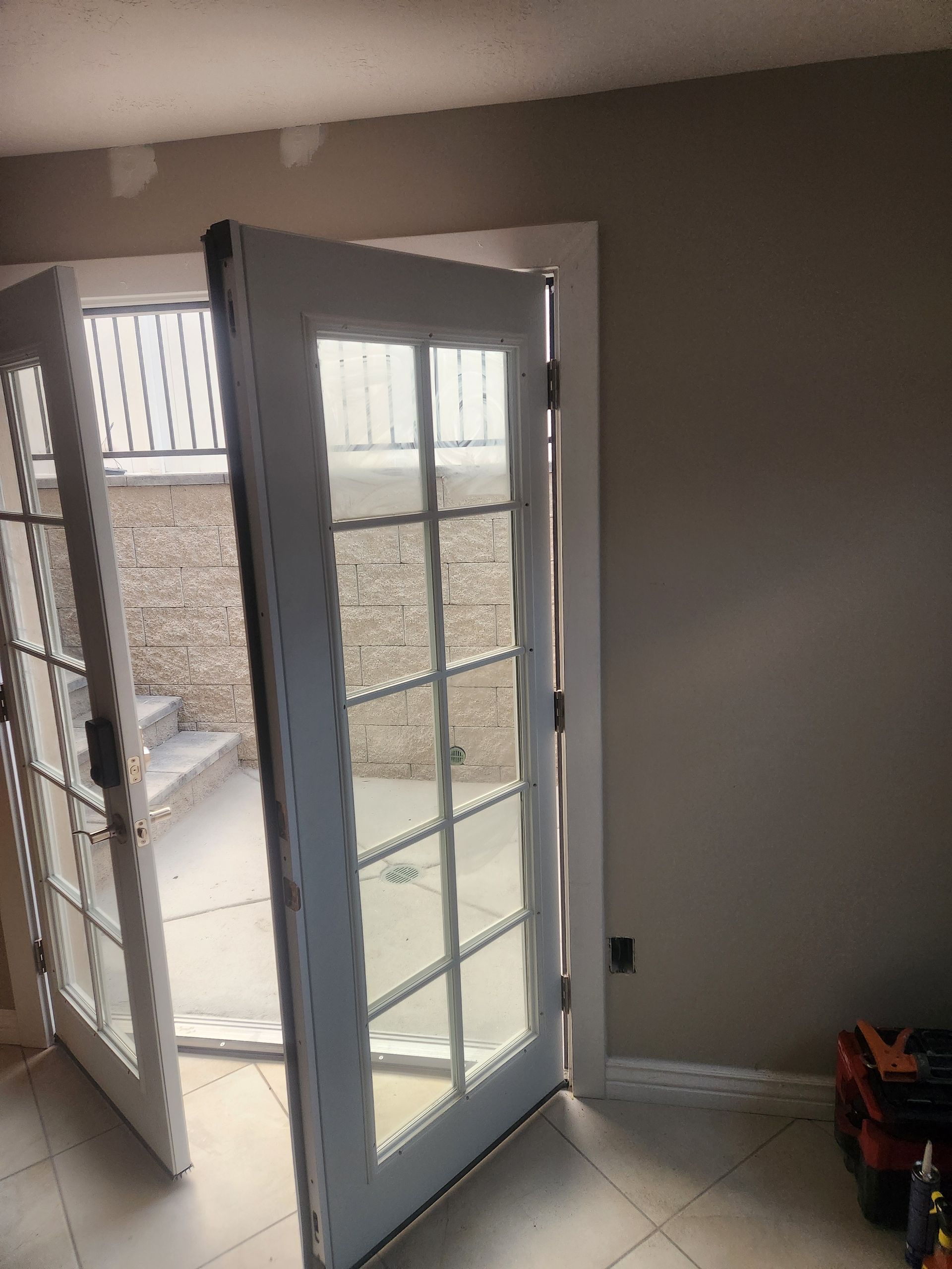 Open French doors in a carpeted room, leading to a sunlit outdoor patio.